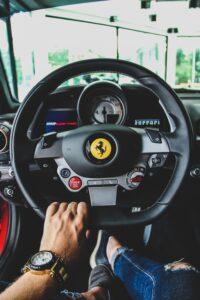 Fahrersicht innen eines Ferraris, Hand am Lenkrad.