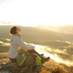 Frau atmet frische Luft auf dem Gipfel eines Berges