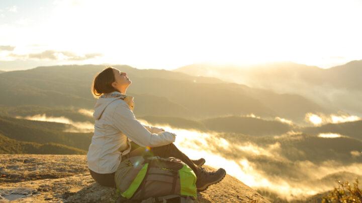 Frau atmet frische Luft auf dem Gipfel eines Berges
