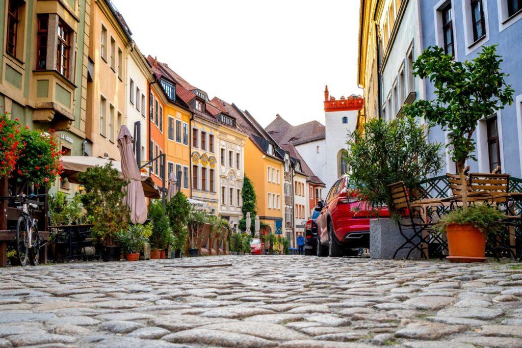 Malerische Altstadt mit Kopfsteinpflaster, gesäumt von historischen Gebäuden, Cafés und Pflanzen – klassischer Bodenbelag mit Charme.