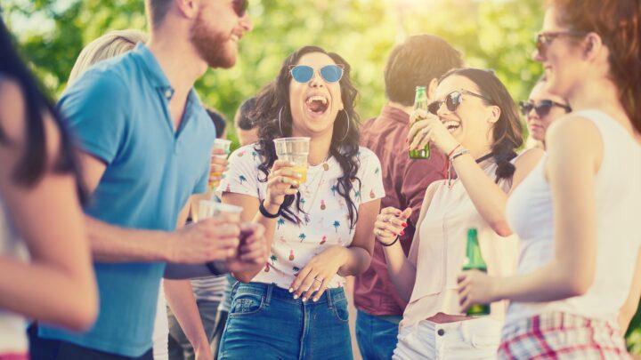 Lachende junge Gruppe feiert im Freien | Glühweinbecher