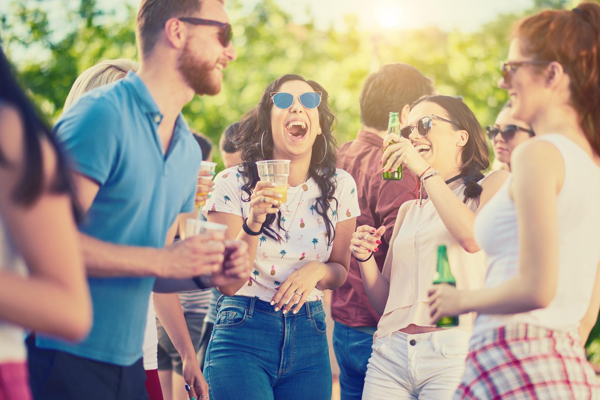 Lachende junge Gruppe feiert im Freien | Glühweinbecher